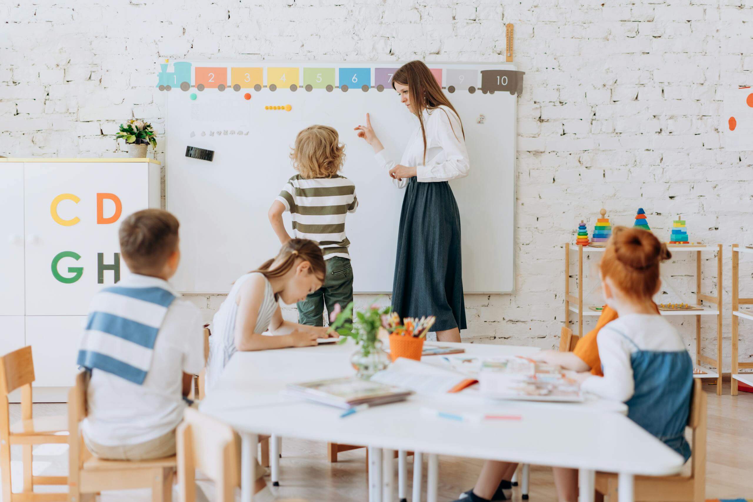Teacher instructing children in a colorful classroom focused on learning activities.